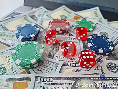 Laptop online casino and poker. Laptop keyboard and chips with dice and money cash dollars on green game table Stock Photo