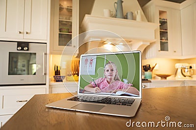 Laptop screen on table with caucasian schoolgirl writing in book while studying online in classroom Stock Photo