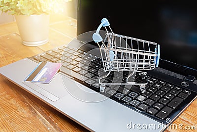 Laptop, small shopping trolley or cart and credit card on wooden table. Internet shopping concept Stock Photo