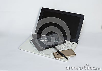 a laptop, a tablet with a cracked screen, smartphones on a light background. Stock Photo