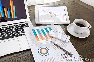 Laptop, tablet ,smartphone with financial documents on wooden table Editorial Stock Photo