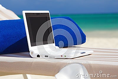 Laptop and towel on the beach chaise longue Stock Photo