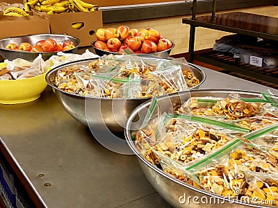 Large amounts of mixed snacks, apples in bowls. Cardboard box of bananas. Stock Photo