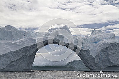 Large through-arch in an iceberg on a cloudy Stock Photo