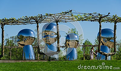 Large baby heads with smiling faces in mirrored metal. Sculpture installation Inner Child by sculptor Ken Kellehe Editorial Stock Photo