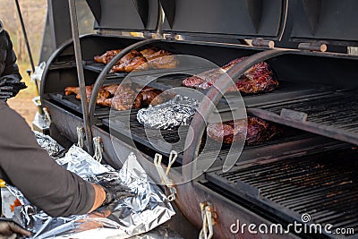large baked piece of meat tenderloin is wrapped in foil for simmering on the grill Stock Photo