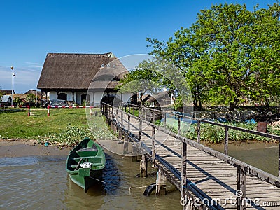 Large, beautiful, traditional, upstairs house in the Danube Delta with wooden pontoon and green anchored boat Stock Photo