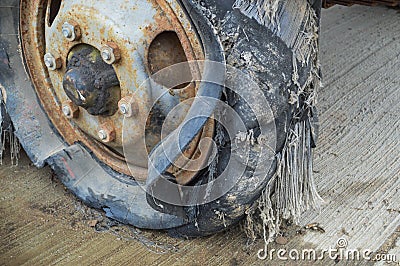 A large black rusty rubber wheel with a torn worn out broken bad old full of tires insecure tire Stock Photo