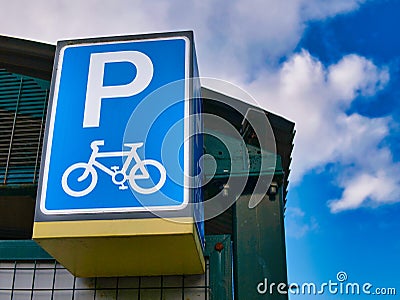 A large blue sign with white graphics marks a secure cycle lockup facility at a local railway station. Editorial Stock Photo