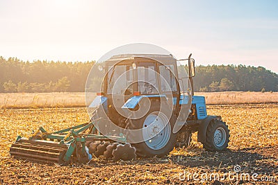 Large blue tractor plow plowed land after harvesting the maize crop on a sunny, clear, autumn day. Stock Photo