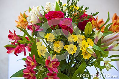 A Large Bouquet of Flowers with Alstromeria Roses and Mums on the edge of a white table Stock Photo