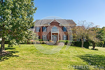 Large brick house with a green lawn. Sunny summer day, cloudless sky Editorial Stock Photo