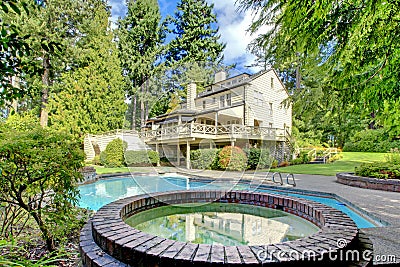 Large brown house exterior with summer garden with pool. Stock Photo