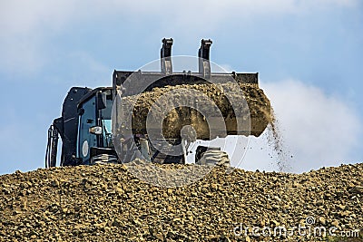 Large bucket with escalator soil frontally on a sunny hot day against the sky. Global construction Stock Photo