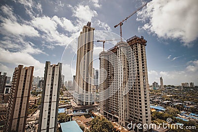 Large buildings with construction cranes under a blue sky with clouds in Mumbai city, India. Editorial Stock Photo