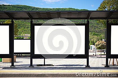 A large bus stop against the backdrop of the mountains with empty advertising banners inside Stock Photo