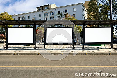 A large bus stop against the background of houses with empty advertising banners inside. Stock Photo