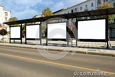 A large bus stop against a beautiful sky in a modern city with empty advertising banners inside Stock Photo