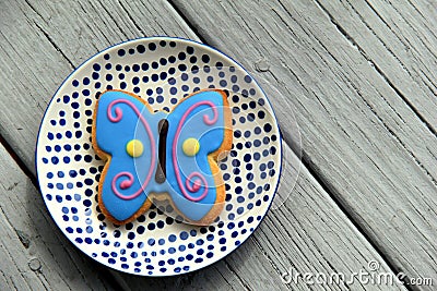 Large butterfly cookie frosted in bright colors, set on pretty plate Stock Photo