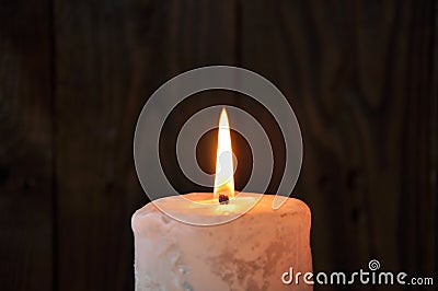 A large candle burns in the darkness on a wooden texture background Stock Photo