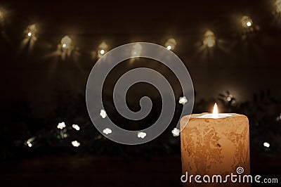 A large candle burns in the dark on a black background. Garland lights and stars. Christmas and New Year Stock Photo