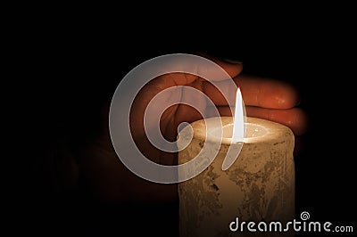 A large candle burns in the dark. On a wooden background. Stock Photo