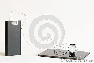 Large capacious external battery - power bank next to a charged gadget - smartphone or tablet and wristwatch. The concept of fast Stock Photo