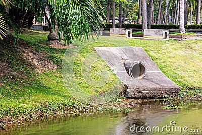 Large cement sewer drain pipe into the lake in the park Stock Photo