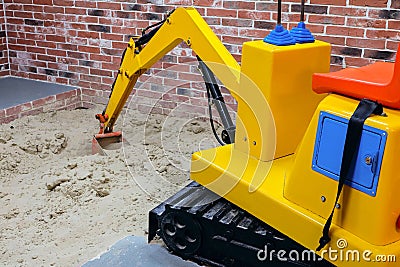 Large childrens yellow excavator in the playroom sandbox Stock Photo