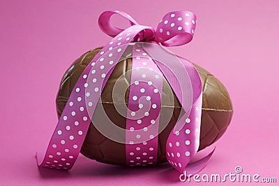 Large chocolate Easter egg with pink polka dot ribbon Stock Photo