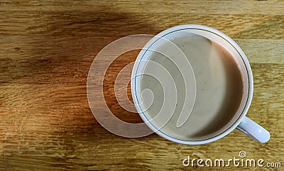 A large coffee mug with milk on a wooden table, top view Stock Photo