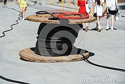 A large coil of electrical wire is lying on the footpath. Construction of infrastructural power lines Stock Photo