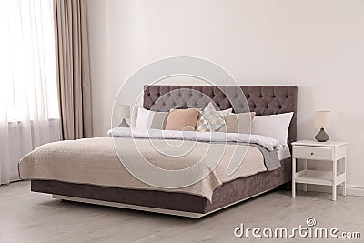 Large comfortable bed near light wall in simple room Stock Photo