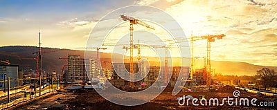 Large construction site including several cranes, with lots of gold sunlight Stock Photo