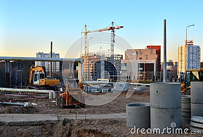Large construction site with working cranes and heavy machinery for road works, wheel loader, bulldozer, excavator. Stock Photo