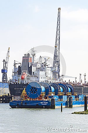 Large cranes are working on getting the huge cargo ships in the Waalhaven in Rotterdam to load and unload Editorial Stock Photo