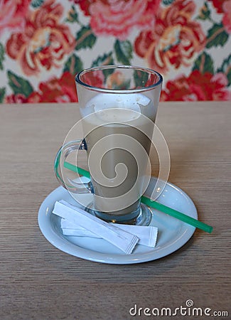 A large Cup of coffee with a saucer and a tube on the table. Wit Stock Photo