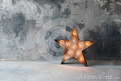 Large decorative retro star with lots of burning lights on grunge concrete background. Beautiful decor, modern design Stock Photo