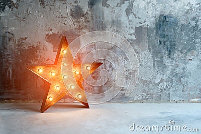 Large decorative retro star with lots of burning lights on grunge concrete background. Beautiful decor, modern design Stock Photo