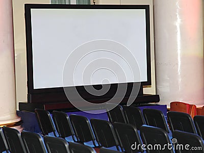 A large demonstration plasma screen and rows of seats for spectators. Stock Photo