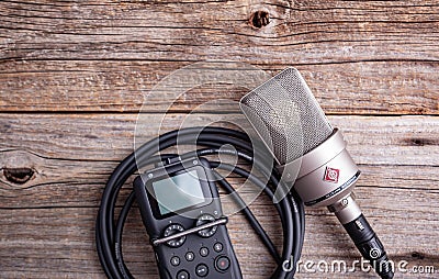 Large diaphragm condenser studio microphone Neumann tlm 103 and Zoom H5 recorder on a wooden background. Editorial Stock Photo
