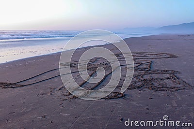 Large drawing on a sand beach picturing adult and a kid next to it Stock Photo