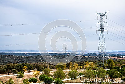 Electric tower surrounded by trees in a field with a cloudy sky in the background Editorial Stock Photo