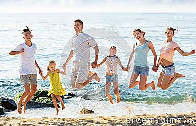 Large family jumping up together on beach on clear summer day Stock Photo