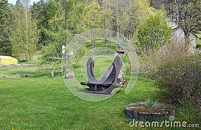 Large five tons ship anchor is mounted on green grass on a sunny spring day Stock Photo