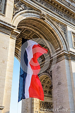 A large french flag fluttering under the Arc de Triomphe in Paris, France Editorial Stock Photo