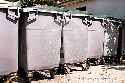 Large garbage containers, trash dumpsters and bins standing in row. Orderly stowed garbage cans ready for separate garbage. Stock Photo