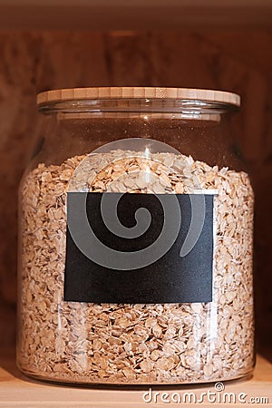 Large glass jar with oats closeup with a black sticker Stock Photo