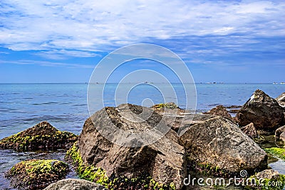 Large granite boulders overgrown with mussels against the background of the sea horizon in Zalizny Port Ukraine. Beautiful Stock Photo