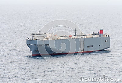 Large gray roll-on/roll-off RORO or ro-ro ships or oceangoing vehicle carrier ship anchor in the open sea. Stock Photo